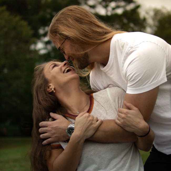 A couple holding each other while about to kiss while sitting in a filed - Couples Photography Session by Amelia and Matt Photo in Cary NC