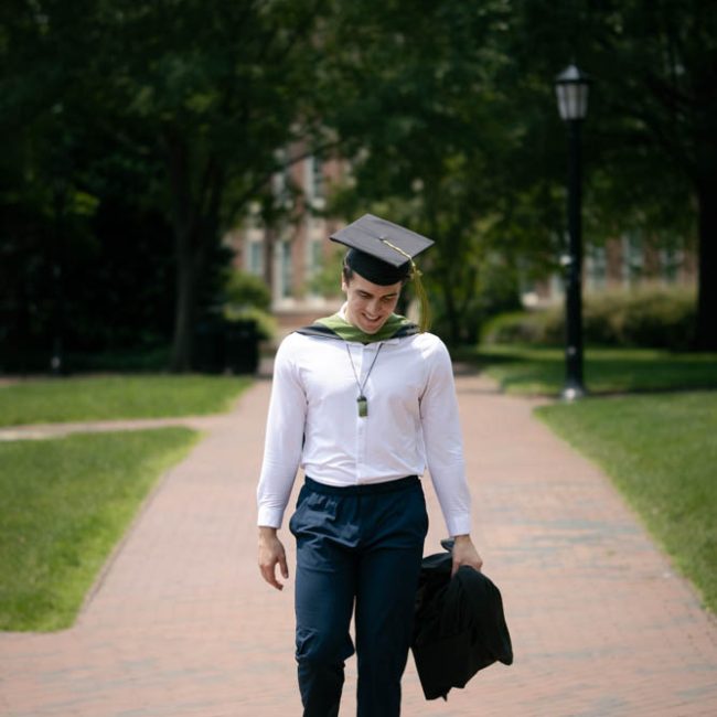 UNC Graduate walking in the the courtyard in Chapel Hill - Amelia and Matt Photo Graduation Photographer