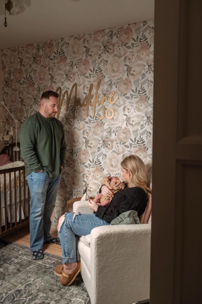 Dad looking at Mom holding their baby in the Nursery - At home newborn photography session in Cary NC