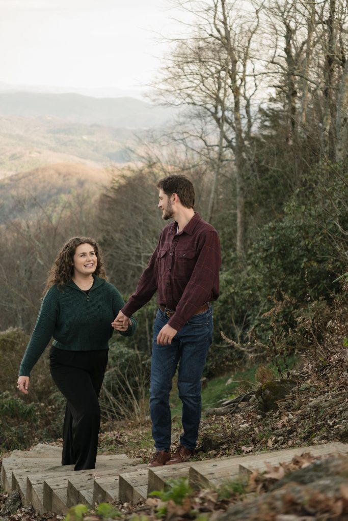 Couple climbing mountain while smiling at each other - couple photoshoot NC