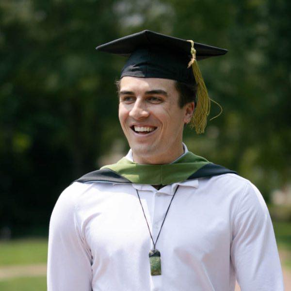 A UNC student wearing his cap and gown during his graduation photo session at UNC Chapel Hill in North Carolina. He is smiling and excited to be photographed graduating