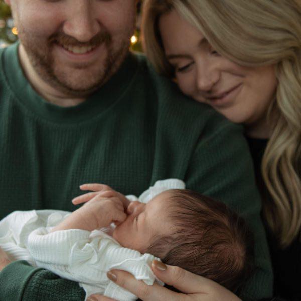 A couple looking down at their newborn baby girl during a newborn photoshoot with Amelia and Matt Photo
