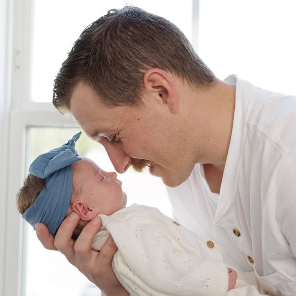A Dad holding their newborn baby and touching their noses together during an in-home newborn photography session with Amelia and Matt photo in Raleigh NC