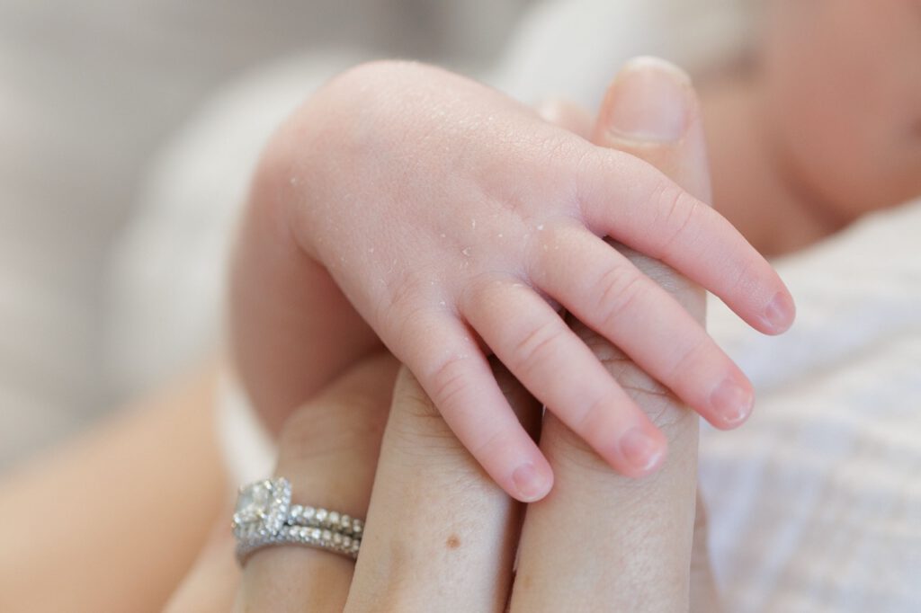a small newborn hand holding his moms finger during an at home newborn photography session in Raleigh NC