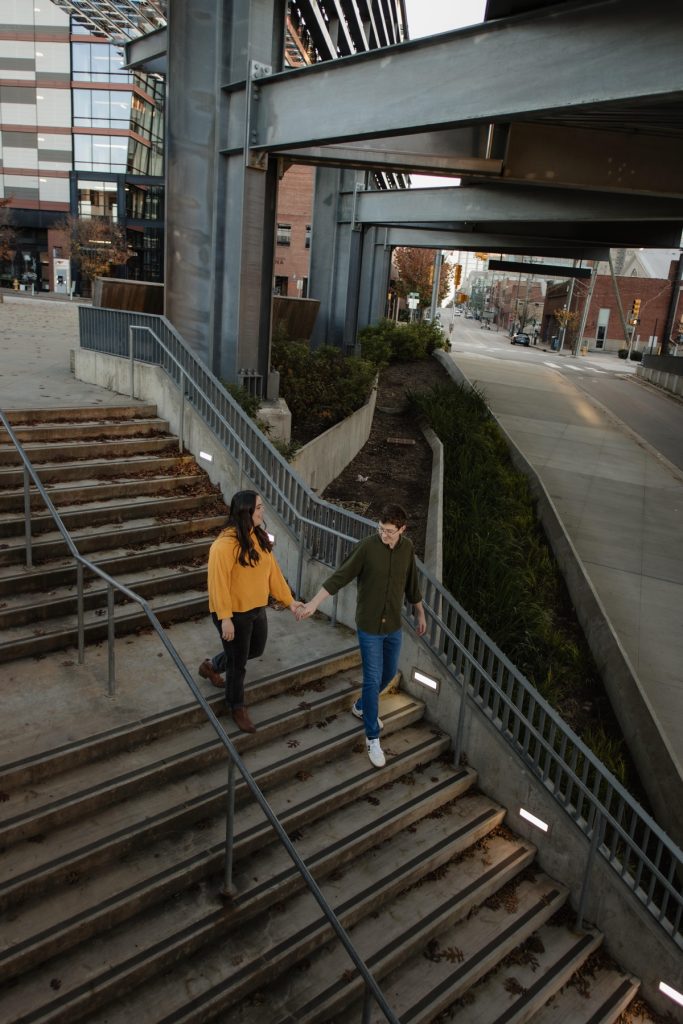 A unique view of stairs and iron beams near the train station in downtown Raleigh NC with a couple walking down the stairs while holding hands