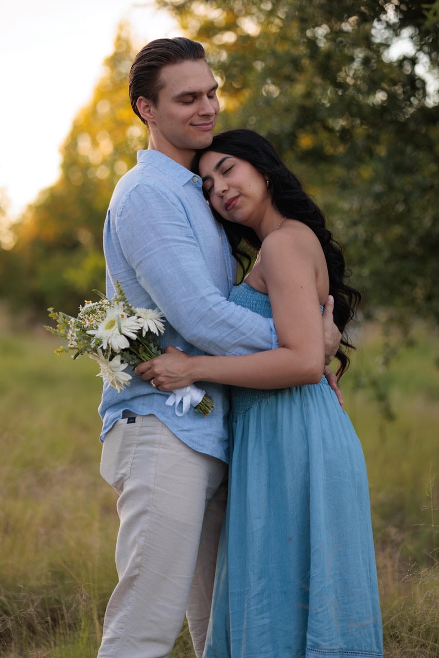 A couple holding each other in the tall grass at the NCMA in Raleigh for their golden hour couples photography session with Amelia and Matt Photo