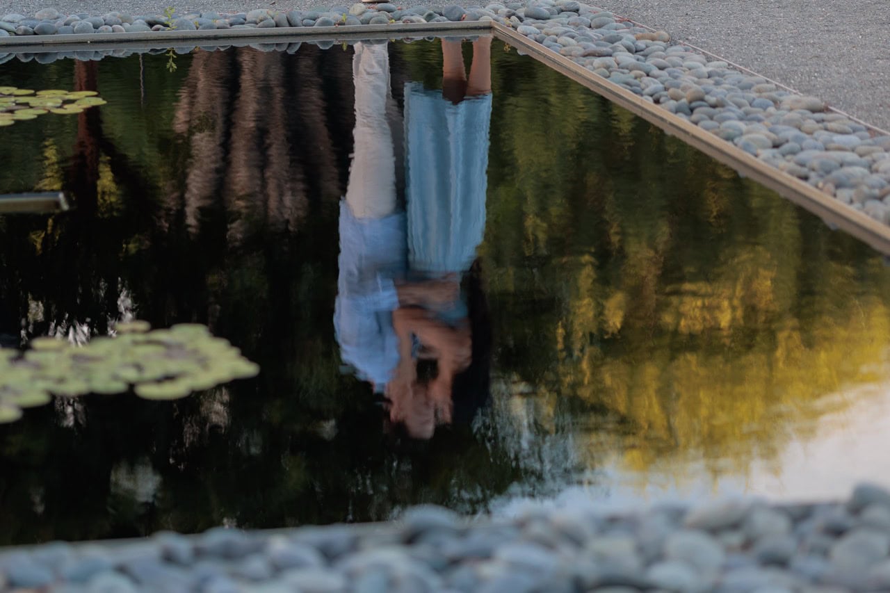 A reflection of a couple kissing seen in the pond at the NC museum of art in Raleigh, the couple is posed for their anniversary photoshoot with Amelia and Matt Photo