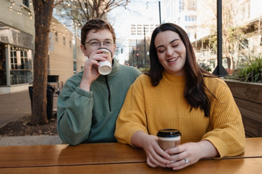 Couple smiling with their coffee from Sir Walter Coffee in downtown raleigh NC. It is their favorite coffee shop and had meaning to their and their relationship