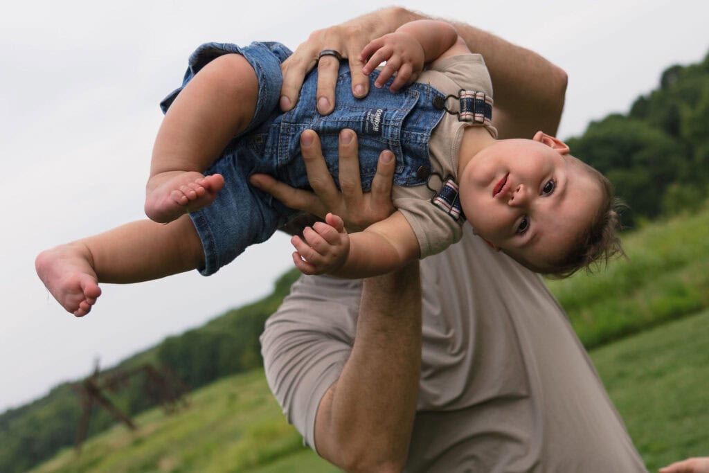 A dad playing with his baby holding him up in the air and spinning him around