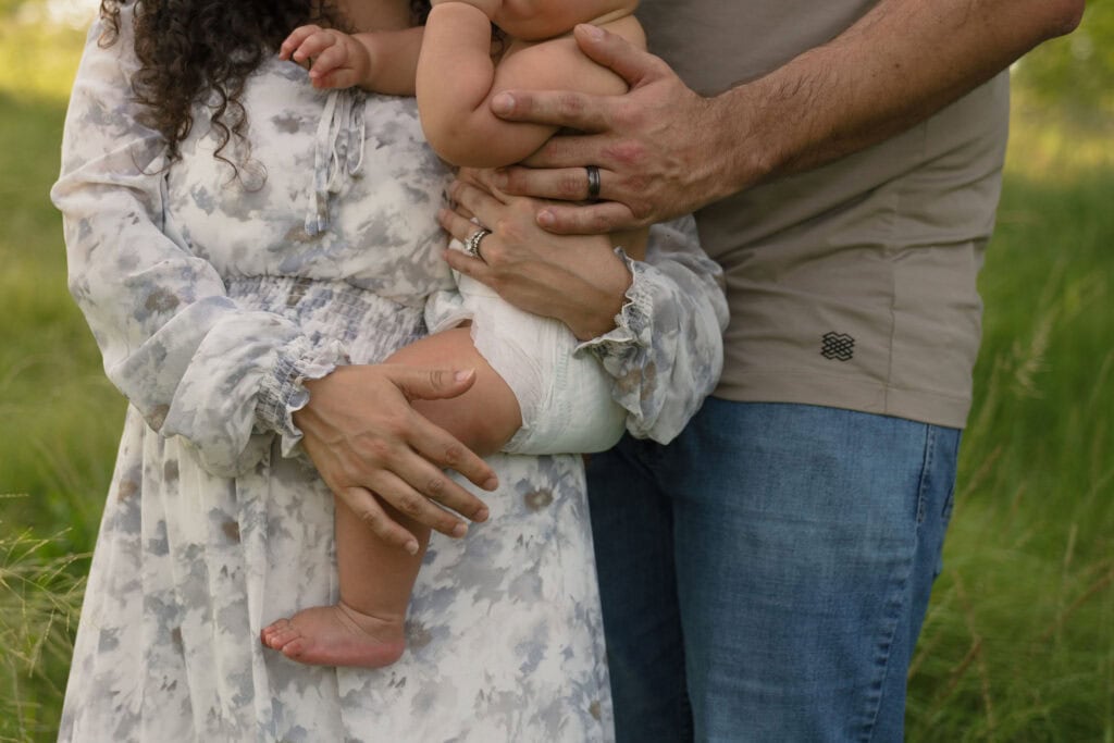 A close up photograph of parents holding their toddler