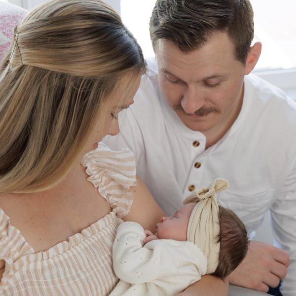 Mom and Dad looking down at their newborn baby in an in-home newborn photography session in Raleigh NC