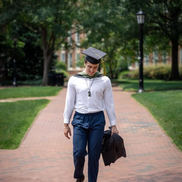 UNC Graduate walking in the the courtyard in Chapel Hill - Amelia and Matt Photo Graduation Photographer